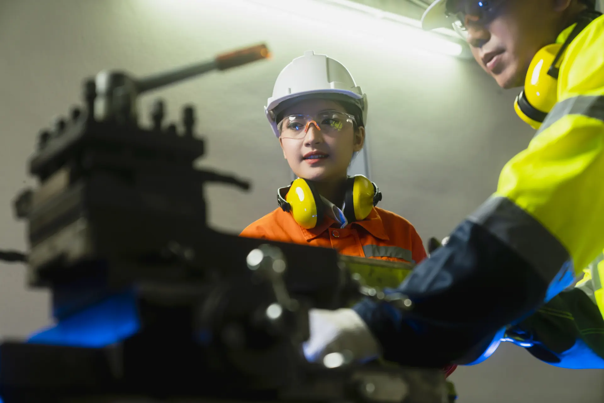 Engineers in hard hats working on industrial machinery