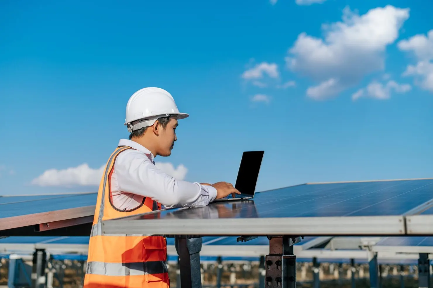 Engineer with a laptop beside solar PV panels